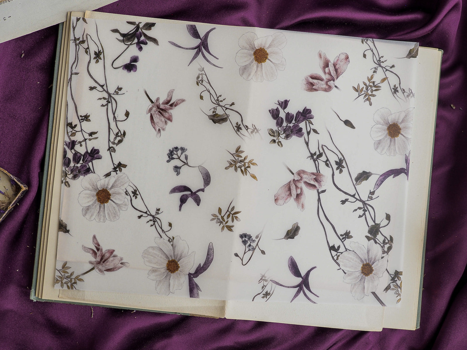 Elegant planner spread featuring muted watercolor botanical illustrations of white and mauve wildflowers, delicate stems, and sprawling floral vines.
