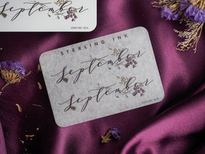 Elegant September month sticker featuring delicate, brown calligraphy and surrounding sepia-toned botanical wreath designs for journaling or scrapbooking.