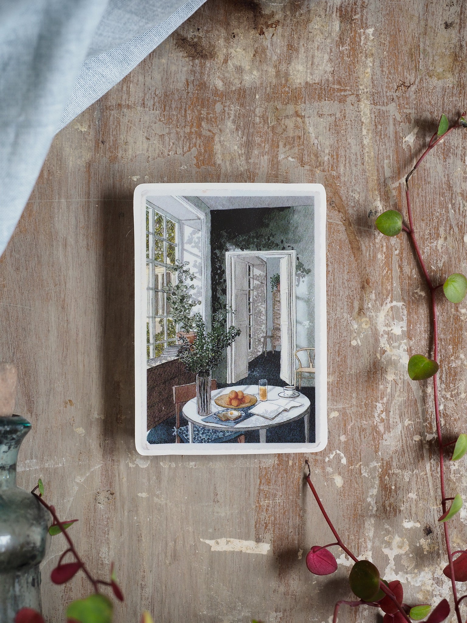 Sticker image of a cozy, sunlit breakfast table featuring pastries, coffee, and elegant floral arrangements in a rustic dining room setting.