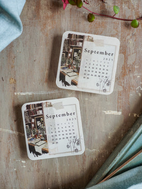 Vintage monthly calendar card featuring September 2025 dates and a rustic illustration of a library interior, printed in muted, earthy tones.