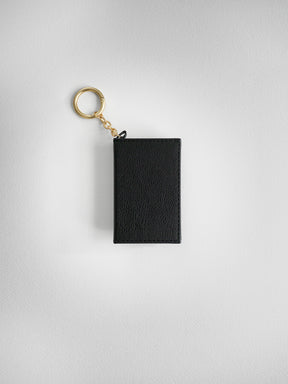 A black textured leather keychain pouch with a gold-tone split key ring and chain, shown against a light gray textured background.
#Color_Onyx