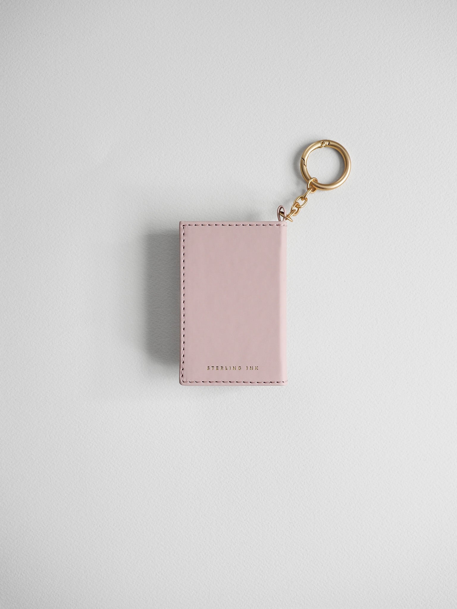 A light pink leather card holder or passport cover keychain with a gold-tone split ring and chain, shown on a clean light gray background.
#Color_Fairyfloss