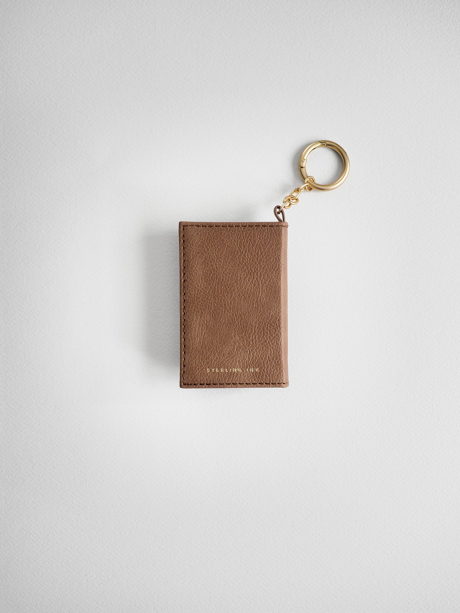 A brown textured leather card holder keychain with a gold-tone split ring and chain, shown on a light gray background.
#Color_Caramel
