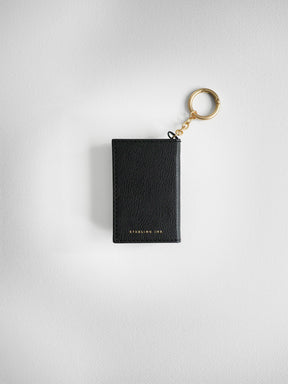 A black textured leather card holder keychain with gold hardware and 'STERLING INK' branding, shown on a light gray textured background.
#Color_Onyx