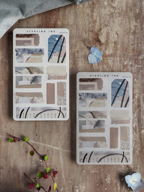 Sheets of abstract torn tape stickers featuring strips in muted, neutral tones, including beige, dusty blue, and soft gray, perfect for journaling.