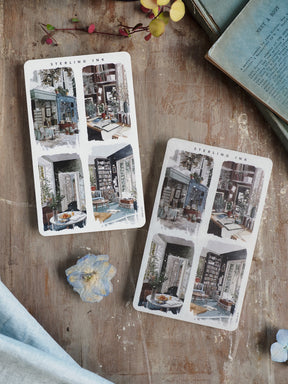 Two sheets of "Sterling Ink" stickers featuring detailed, whimsical watercolor illustrations of quaint, cozy street scenes, shops, and European-style architecture.