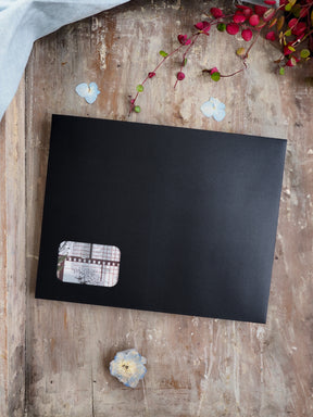 Sleek black journal or planner cover featuring a small, detailed patterned accent patch for a seasonal subscription kit.