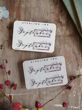 Elegant sticker set for planning featuring "September" written in black calligraphy, decorated with delicate rustic botanical elements and a decorative liner.