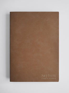 A brown textured faux-leather 2027 common planner with gold foil text in the bottom right corner, displayed on a light gray background.
#Color_Caramel