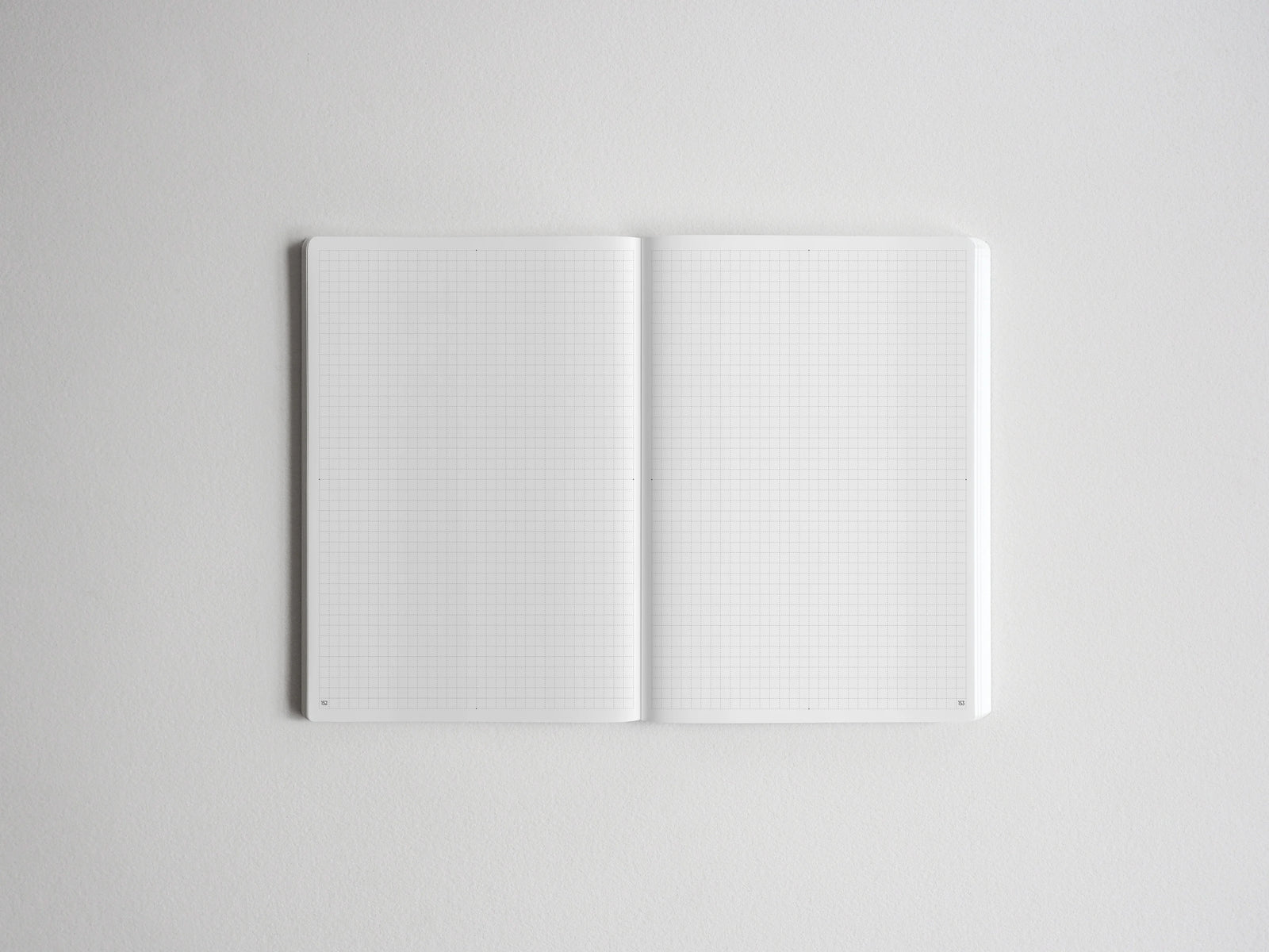 Open spiral notebook showcasing two blank pages of light gray graph paper, perfect for creative sketching, journaling, or academic tracking.
