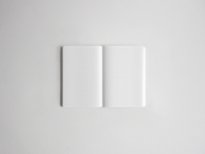 Open notebook displaying white graph paper grids on both pages, ideal for planning, drawing, or journaling.
