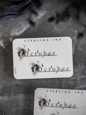 Rustic, cream-colored monthly planner sticker featuring elegant, calligraphic script that reads "October," designed for seasonal journaling.