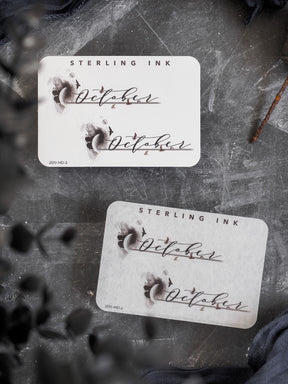Decorative label featuring the name "October" in elegant script lettering, set within a soft watercolor wash design, suitable for themed journaling or planning.