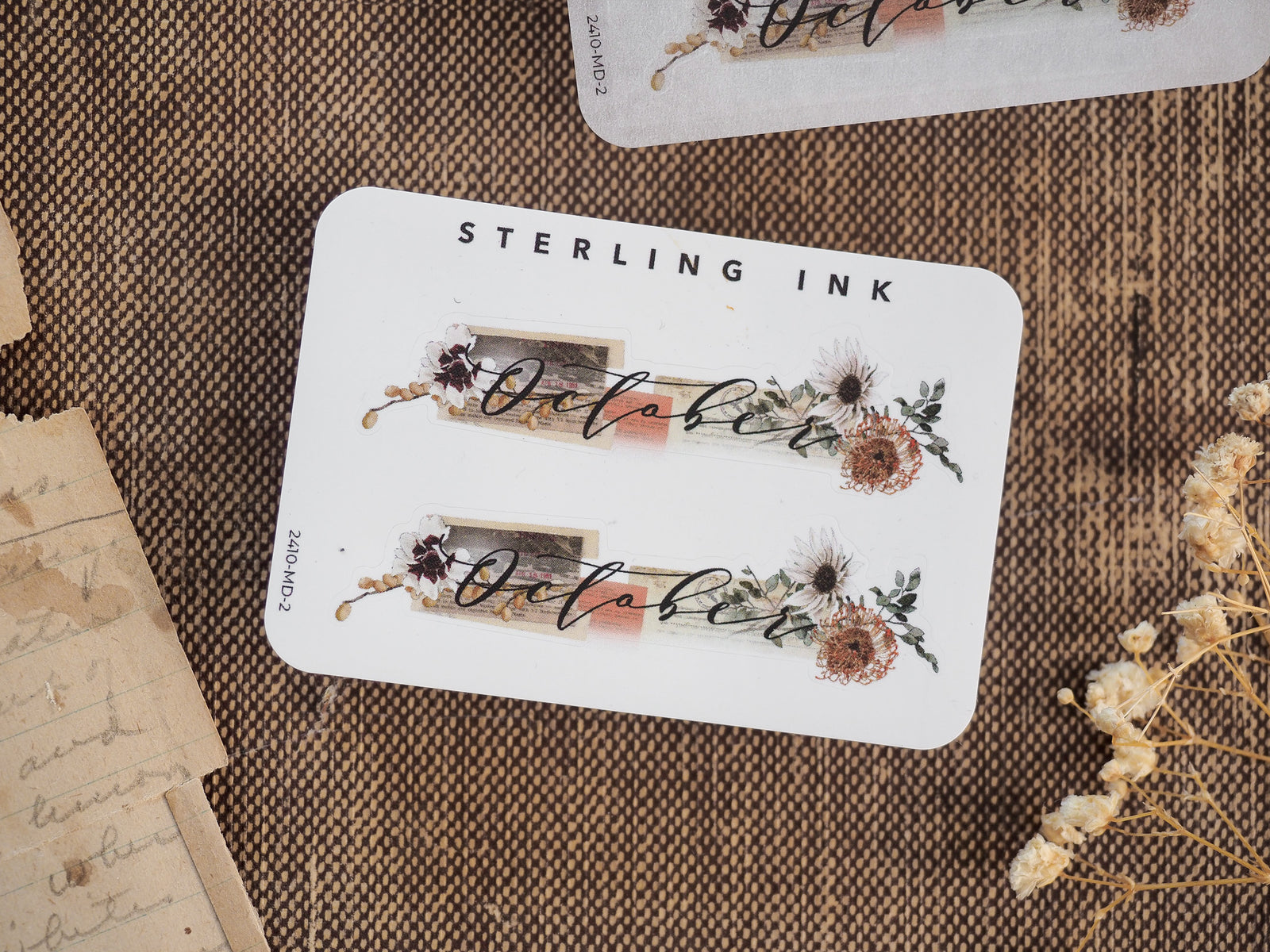 White label sticker featuring the script word "October" surrounded by rustic, deep-toned watercolor floral and botanical illustrations for autumn planning.