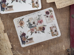 A sticker sheet adorned with muted vintage floral clusters, delicate greenery, and accented with shimmering silver foil corners.