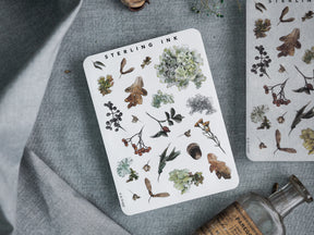 "Elements Stickers - October 2023" featuring a botanical arrangement of detailed stickers depicting autumn leaves, berries, and rustic natural elements.