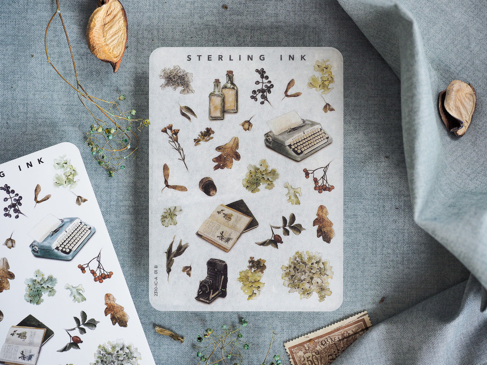Pale sticker sheet featuring rustic botanical elements, including dried leaves, ink bottles, and vintage writing tools, titled "Sterling Ink."