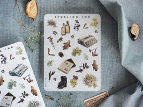 Pale sticker sheet featuring rustic botanical elements, including dried leaves, ink bottles, and vintage writing tools, titled "Sterling Ink."