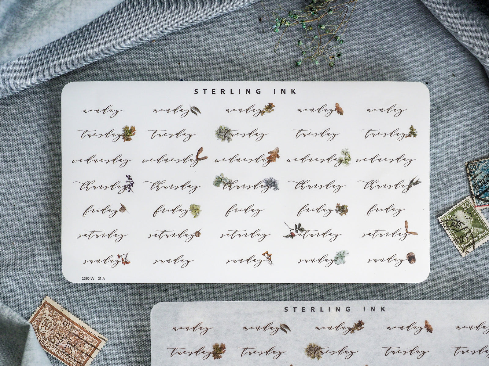 A decorative sheet of weekly sticker labels for planners, featuring the days of the week (Monday-Sunday) in a rustic, hand-lettered style with delicate brown and green botanical accents.