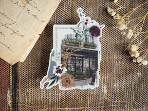 Decorative clear vinyl sticker featuring an autumnal illustration of a lush, vine-covered greenhouse window displaying rich purple and deep red blooms.
