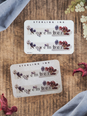 Elegant November month sticker featuring "Sterling Ink" branding and realistic clusters of purple and burgundy dried florals.