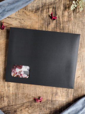 Large matte black planner or journal with a cream-toned accent sticker showcasing muted, autumnal watercolor florals, ready for November planning.