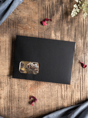 Matte black journaling sheet featuring a central, distressed sticker with a faded, rectangular, sepia-toned vintage design for decorative planning.