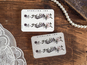 A set of two November month stickers featuring elegant journaling designs with watercolor floral clusters in shades of mauve, purple, and sage green.