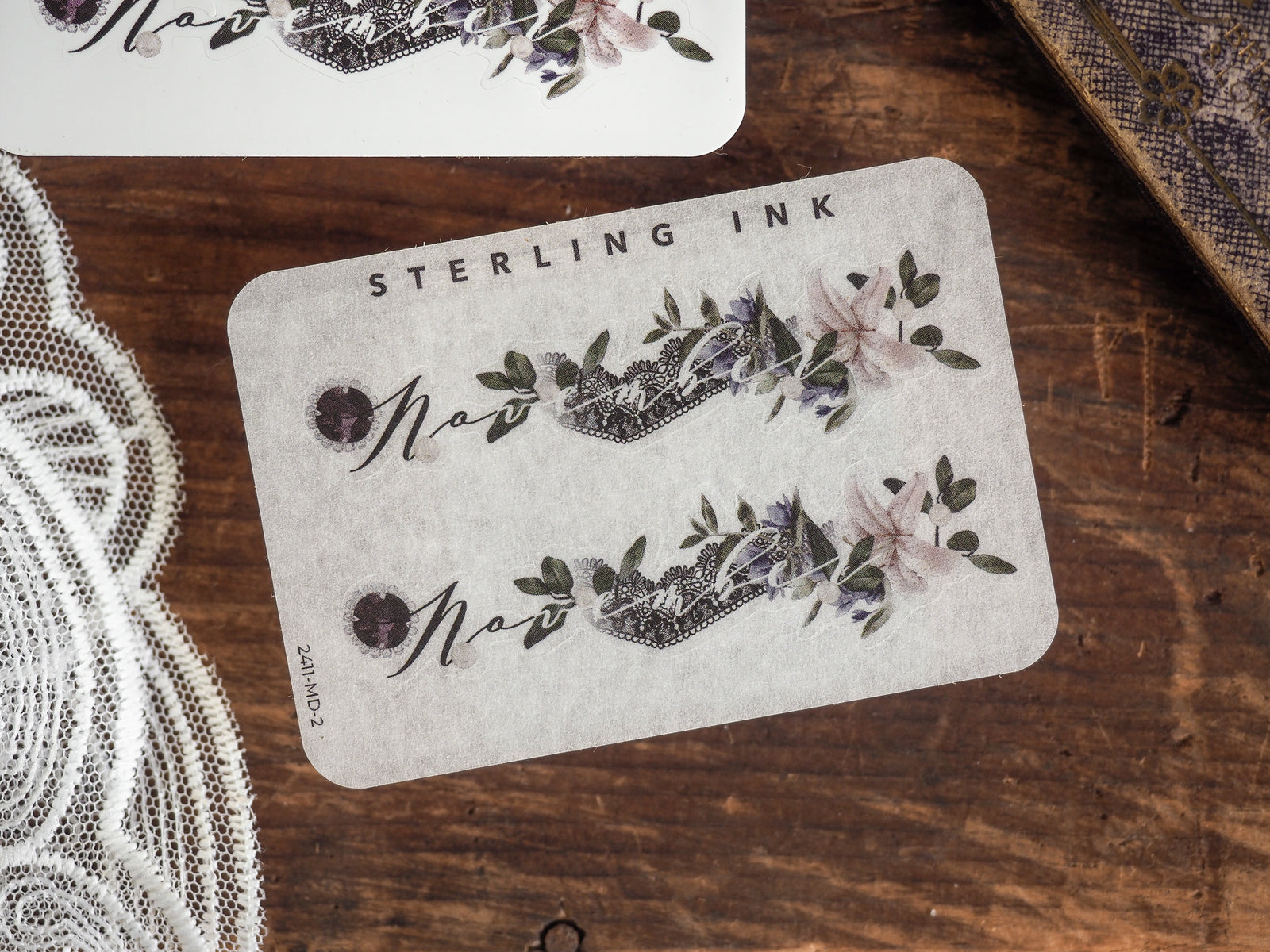 Decorative November month sticker featuring a purple and gray floral wreath design, personalized with script and "Sterling Ink" branding for journaling.
