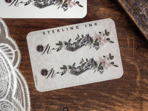 Decorative November month sticker featuring a purple and gray floral wreath design, personalized with script and "Sterling Ink" branding for journaling.
