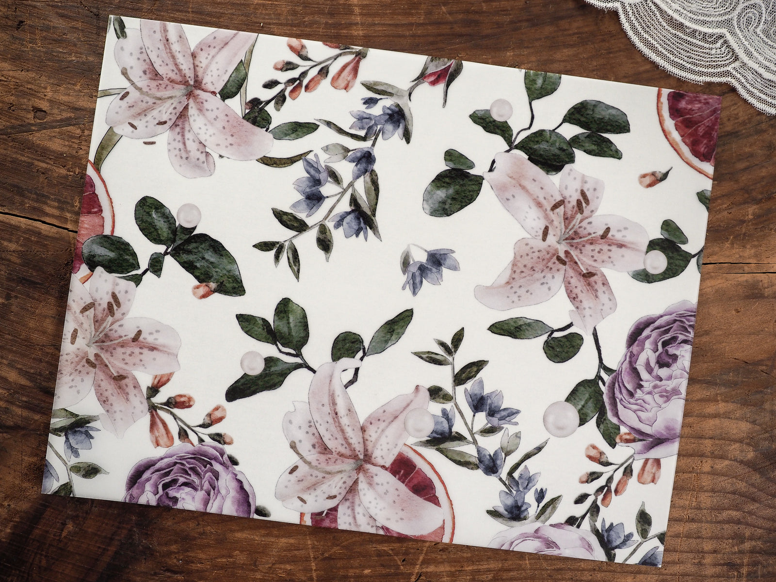 Elegant watercolor botanical print featuring soft mauve lilies, lush green foliage, and delicate blue woodland accents on white vellum.