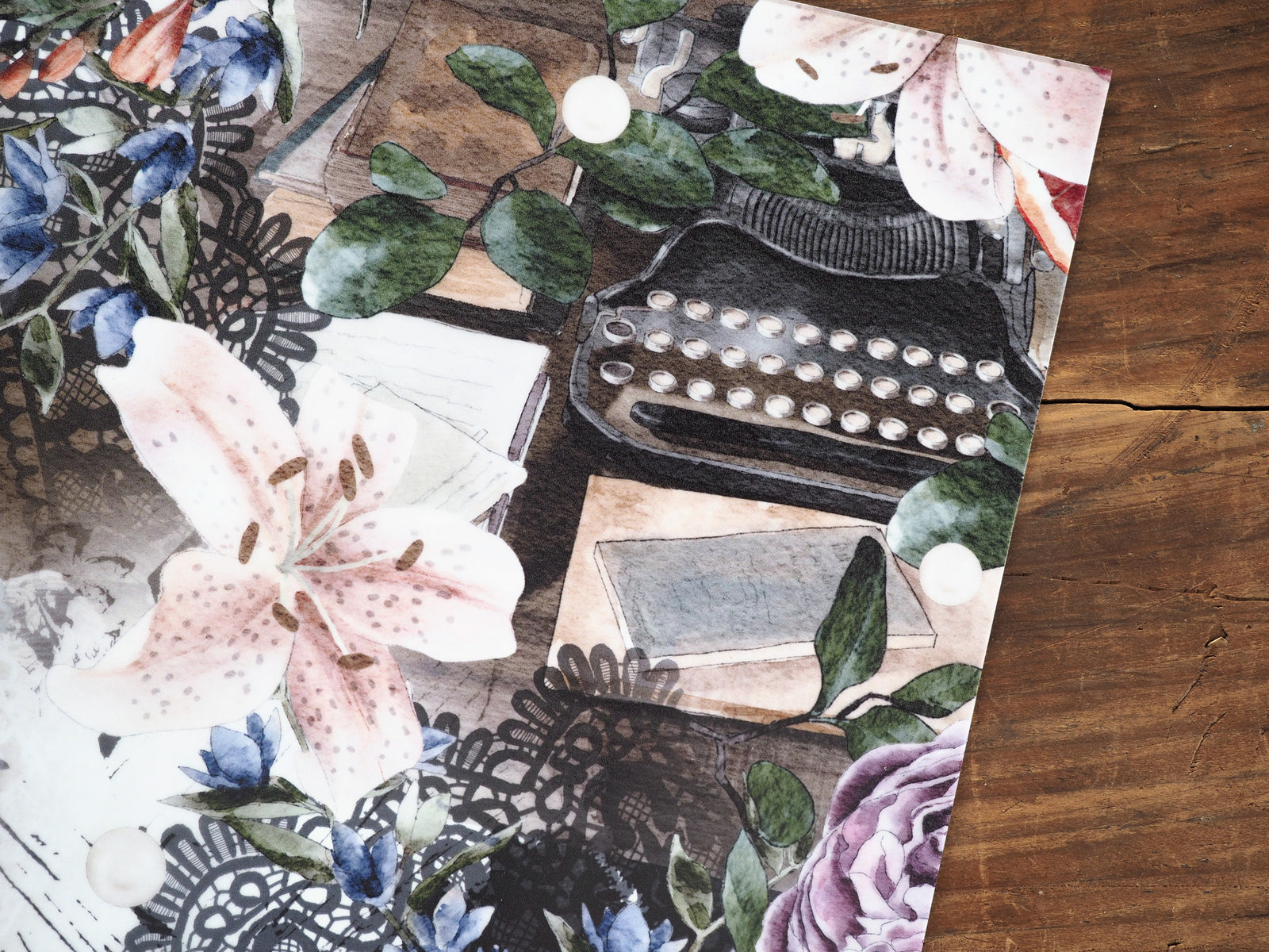 Botanical planner cover featuring 'Vellum - November 2024' with watercolor lilies, deep blue accents, green eucalyptus foliage, and vintage lace patterns.