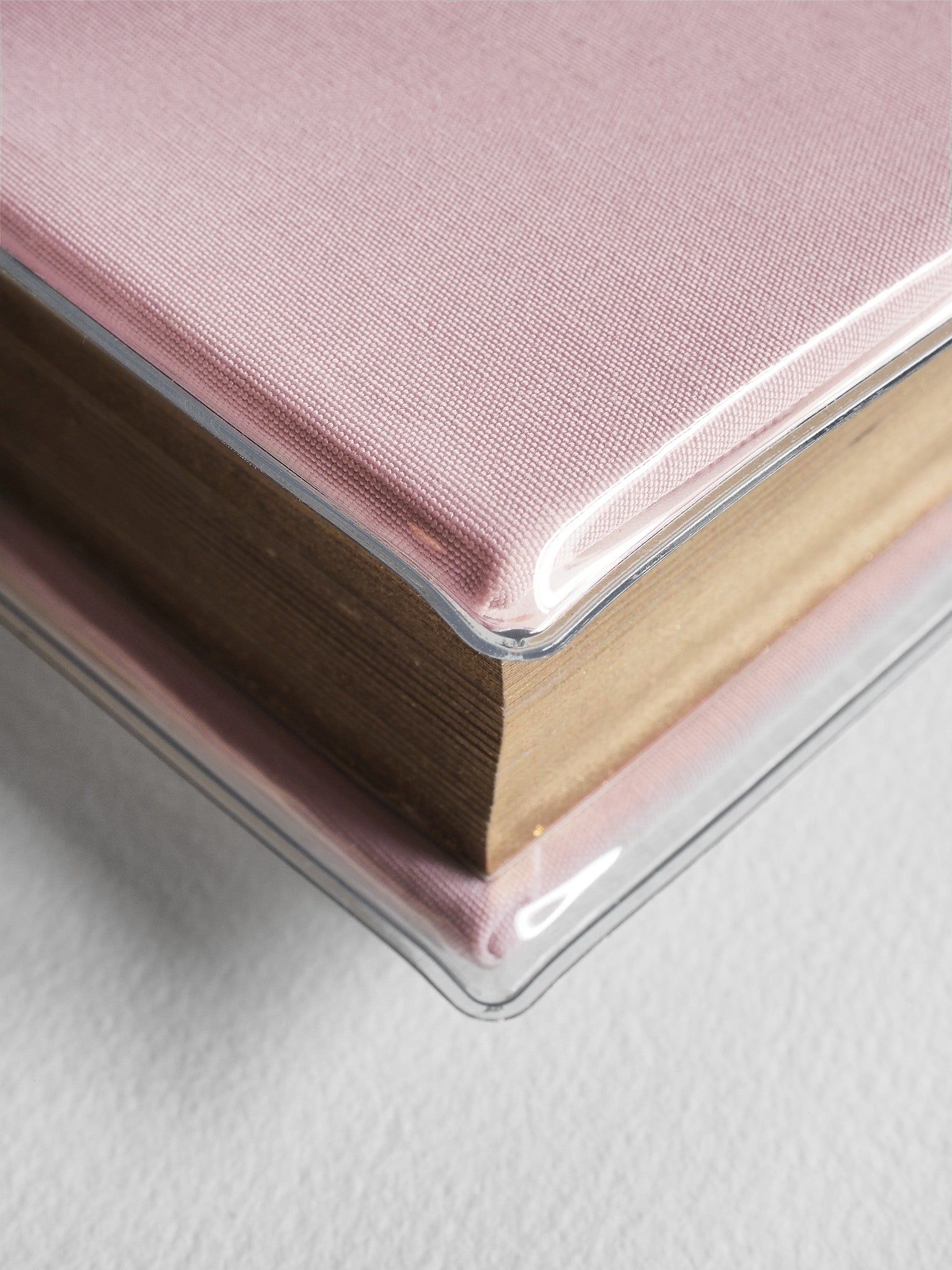 Dusty rose textured hardcover planner featuring a bound book design protected by a crystal-clear plastic sleeve.