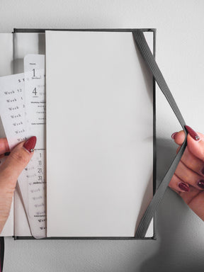 Functional A5 undated planner displaying detailed week-at-a-glance and month-by-month date grids within a professional gray hardcover binding.