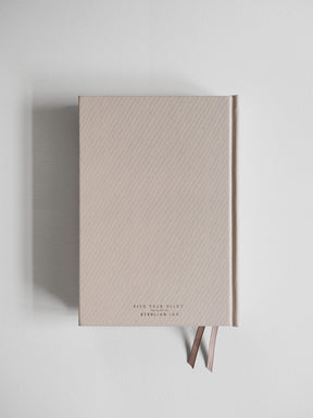 Minimalist A5 hardcover diary in soft, neutral beige, featuring subtle dark typography that indicates the five-year format.