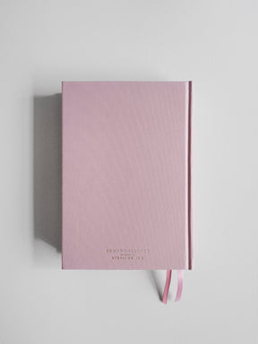 A pink hardcover notebook with a subtle diagonal ribbed texture and a matching pink ribbon bookmark, displayed on a light gray background.
#Color_Seashell