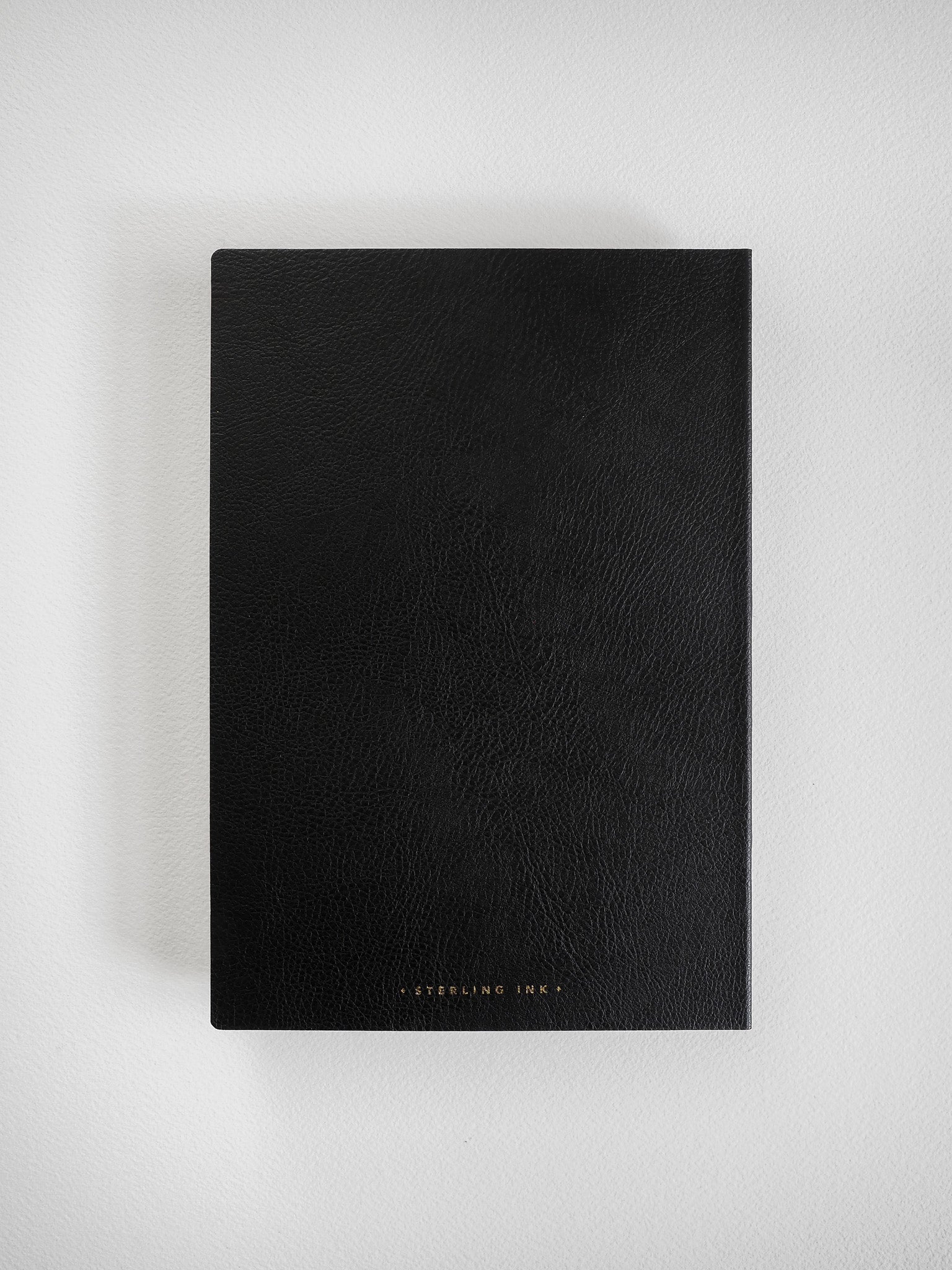 Elegant A5 grid notebook bound in matte black faux leather, featuring minimalist branding that reads 'STEELING INK' at the bottom.
