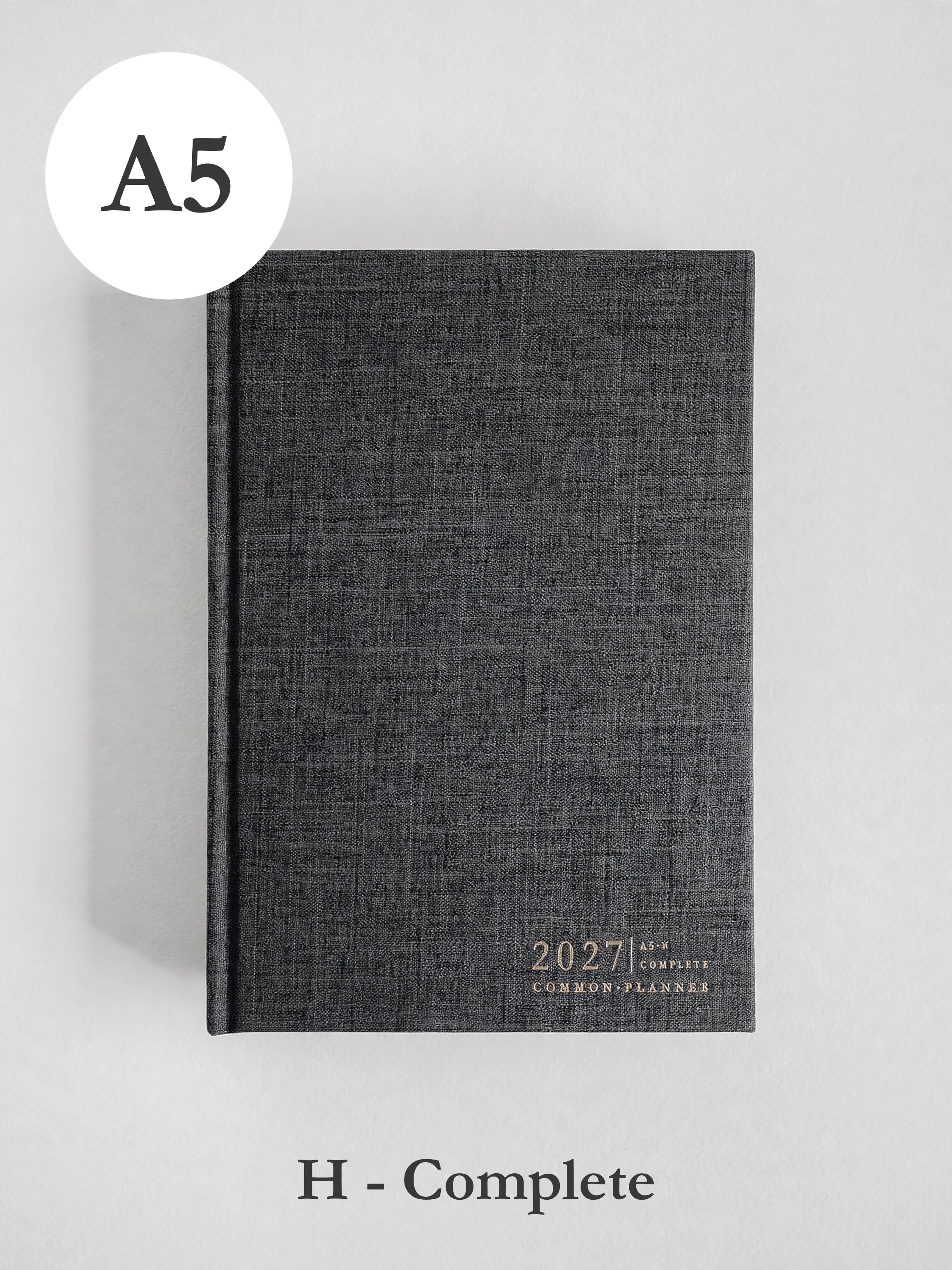 A dark gray textured hardcover planner shown closed on a light gray background, with an A5 size circle label at top left and 'H - Complete' text below.
#Color_Charcoal