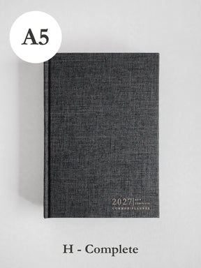 A dark gray textured hardcover planner shown closed on a light gray background, with an A5 size circle label at top left and 'H - Complete' text below.
#Color_Charcoal