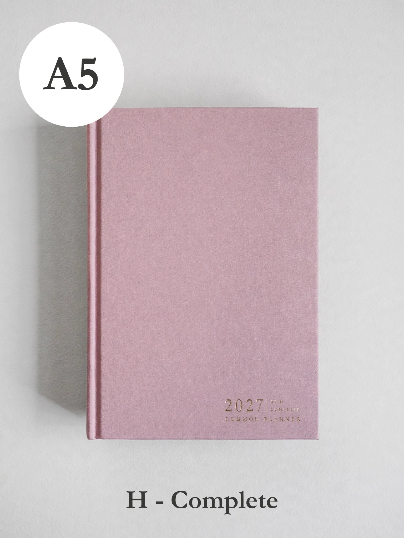 A pink hardcover planner or notebook shown closed on a light gray background, with a white circular label reading A5 at top left and text at bottom reading H - Complete.
#Color_Seashell