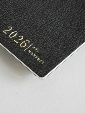 Sleek dark gray A5 monthly booklet cover featuring embossed gold lettering that clearly displays "2026 | A5 | MONTHLY."