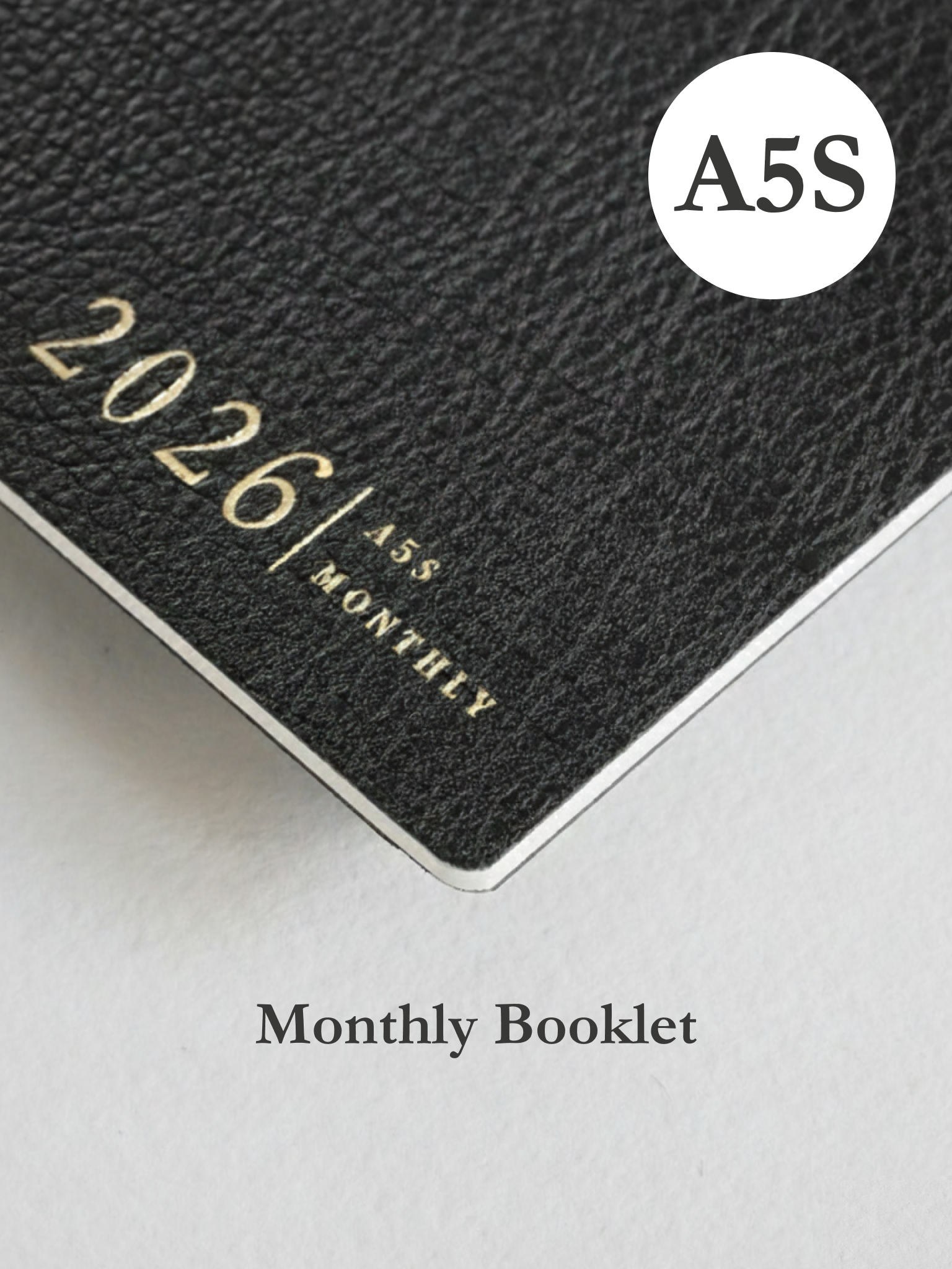 Dark charcoal booklet cover featuring embossed text for "2026," "A5," and "MONTHLY," indicating a structured annual planner.