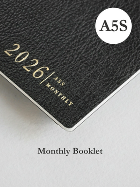 Dark charcoal booklet cover featuring embossed text for "2026," "A5," and "MONTHLY," indicating a structured annual planner.