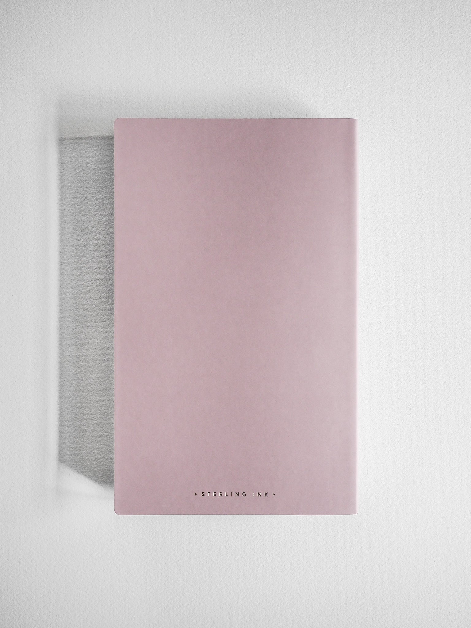 Minimalist A5 grid notebook featuring a soft blush pink cover with discreet "Sterling Ink" branding for writing and sketching.