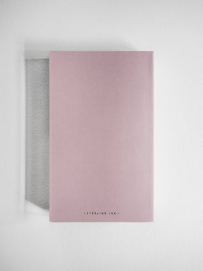 Minimalist A5 grid notebook featuring a soft blush pink cover with discreet "Sterling Ink" branding for writing and sketching.