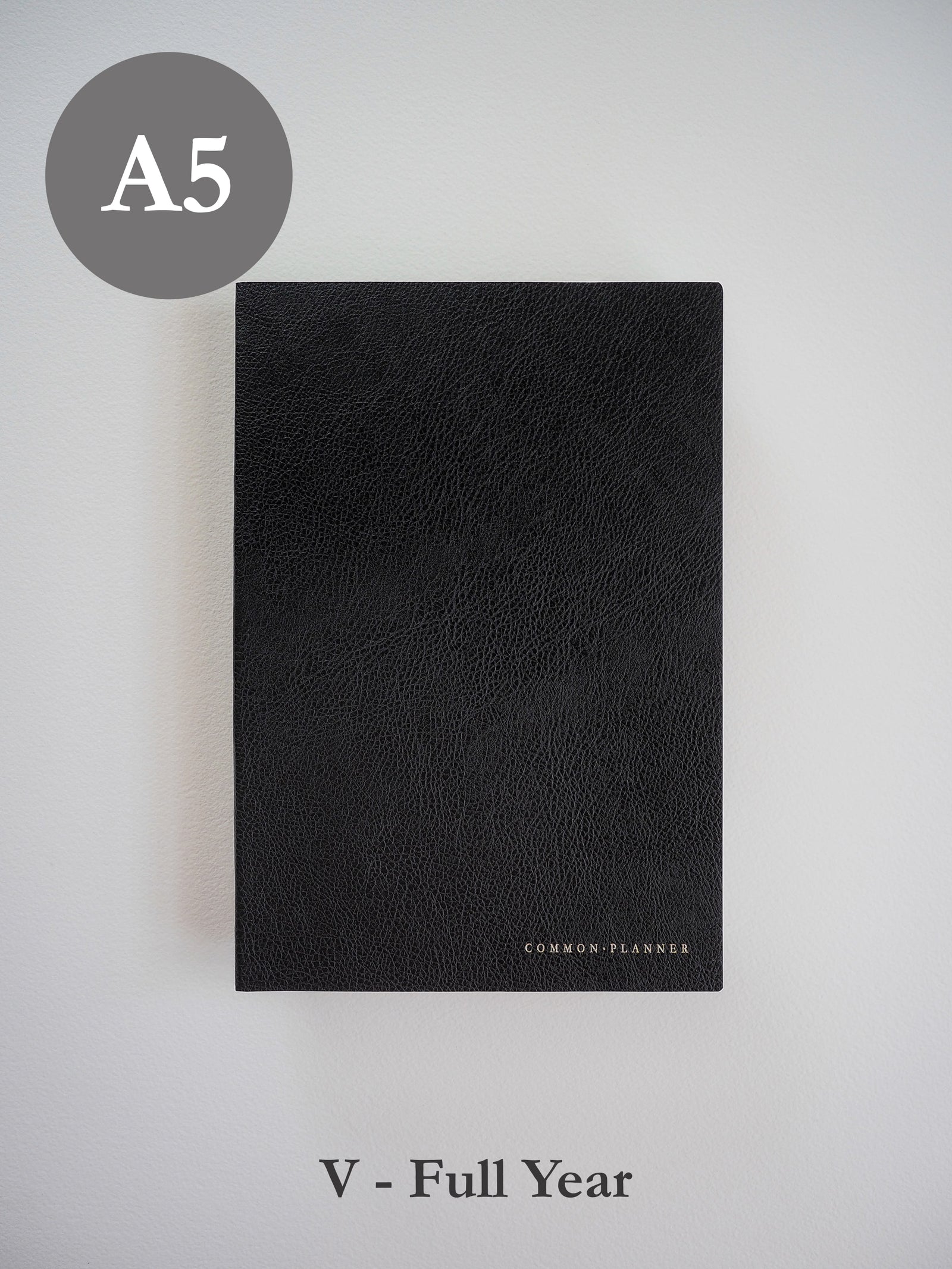 Sleek A5 vertical planner with a richly textured black faux leather cover and minimalist "COMMON•PLANNER" branding.