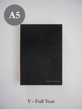 Sleek A5 vertical planner with a richly textured black faux leather cover and minimalist "COMMON•PLANNER" branding.