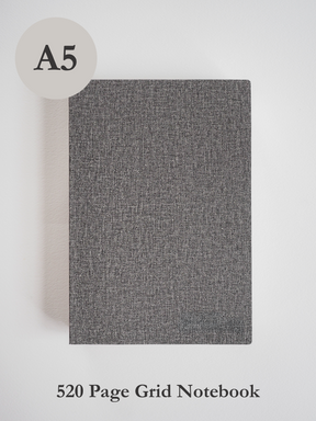 Minimalist A5 grid notebook with a dark charcoal gray, textured linen-like cover, ideal for detailed journaling and writing tasks.