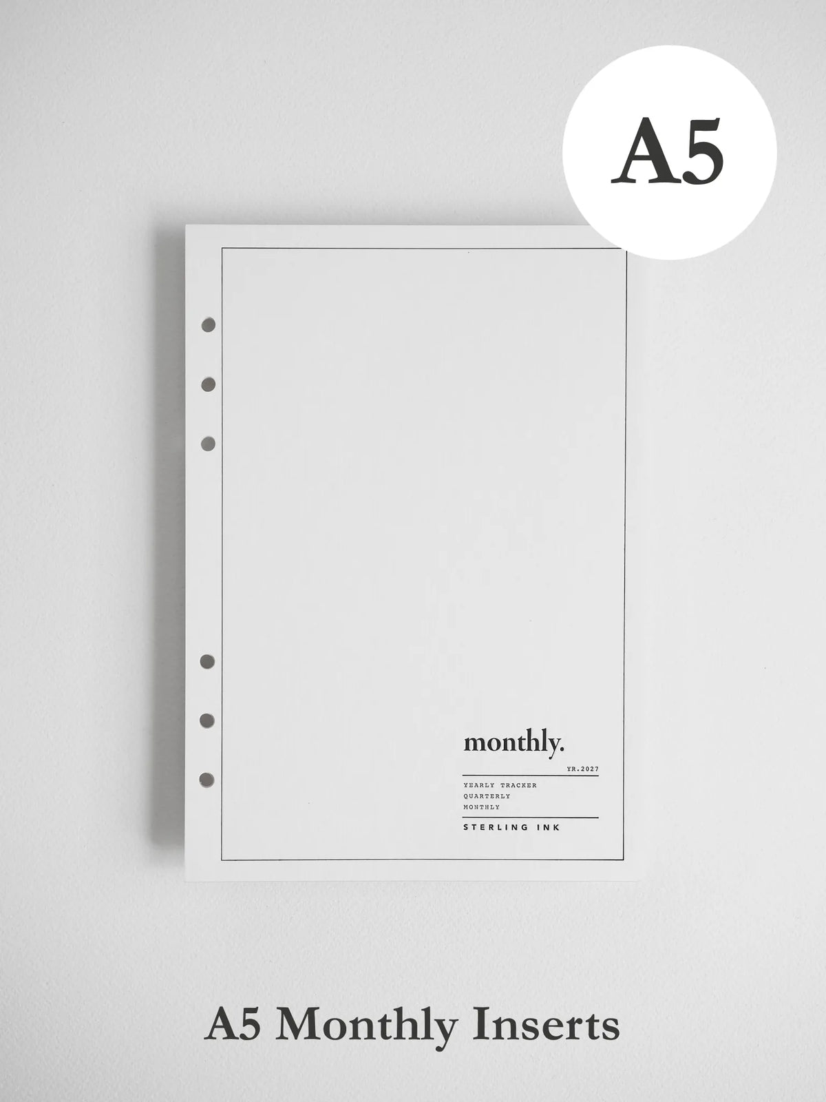 A white A5 monthly insert notebook page with a thin border, five binder holes on the left, and the word 'monthly.' printed near the bottom, shown on a light gray background.
#Size_A5