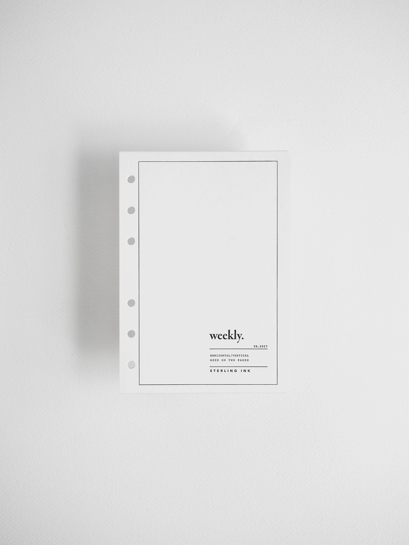 A minimalist white weekly planner insert with a five-hole punch on the left side, featuring the text 'weekly.' and 'STERLING INK' printed in black on the lower right, set against a clean white background.
#Size_A6